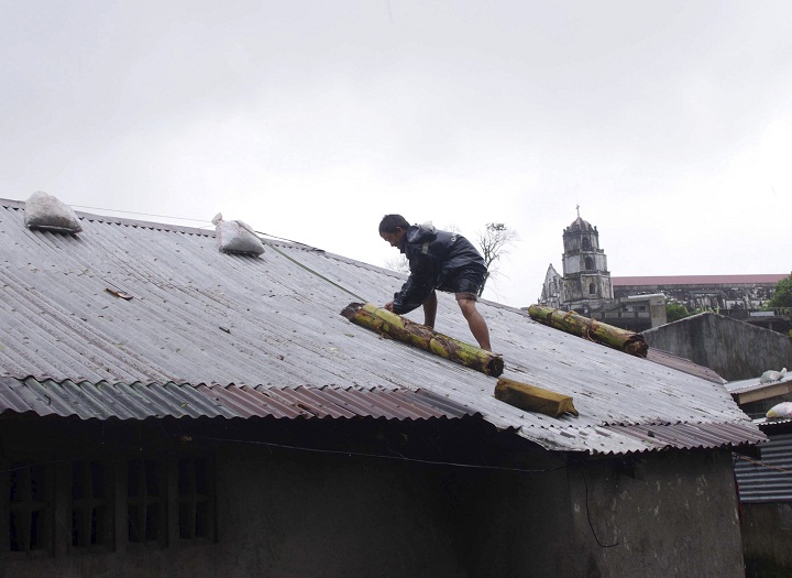 A man reinforces his house with banana stalks as powerful typhoon Haiyan hits Legazpi city, Albay province. (AP Photo/Nelson Salting)