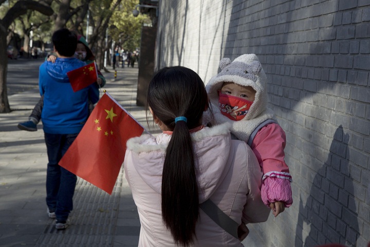 Visitors to the forbidden city carry children holding the Chinese national flags in Beijing, China, Saturday, Nov. 16, 2013. Some 15 million to 20 million Chinese parents will be allowed to have a second baby after the Chinese government announced Friday, Nov. 15, 2013 that couples where one partner has no siblings can have two children, in the first significant easing of the country’s strict one-child policy in nearly three decades.