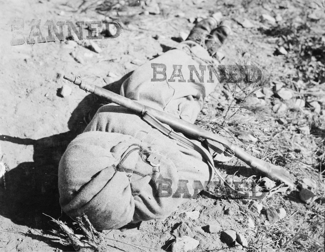 The body of a Canadian infantryman awaits burial in Korea, November, 1951. His identity tag and what appear to be religious medals with text in French are attached to the blanket. A battlefield censor forbade publication of the image. 