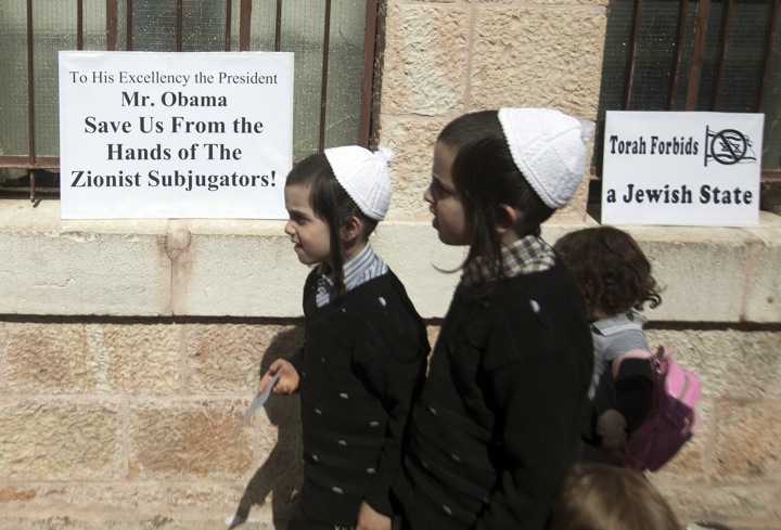 Ultra-Orthodox Jewish children walk past slogans of the Neturei Karta movement during a rally held by the small anti-Zionist Jewish faction, that opposes Israel's existence, in Jerusalems Mea Sharim district on March 20, 2013