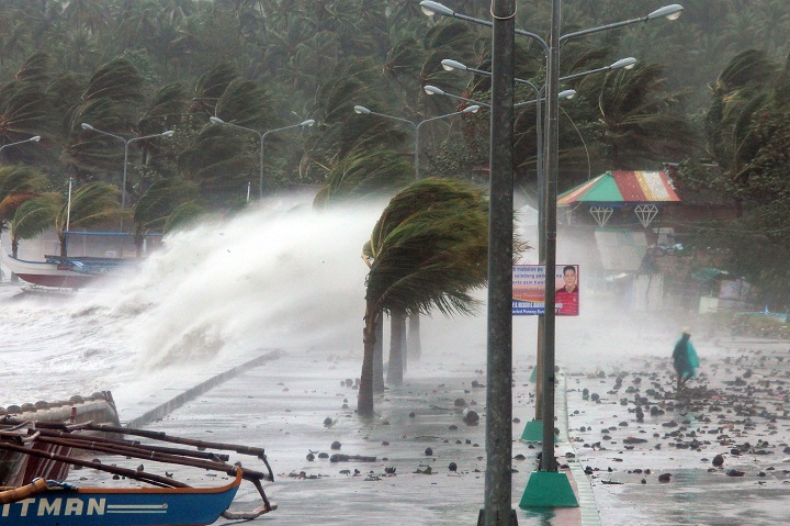 A resident walks past high waves pounding the sea wall amidst strong winds as Typhoon Haiyan hit the city of Legaspi, Albay province, south of Manila. 