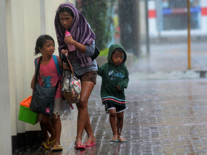 A mother and her children brave heavy rains as they head for an evacuation center amidst strong winds as Typhoon Haiyan pounded Cebu City, in central Philippines. ( STR/AFP/Getty Images)