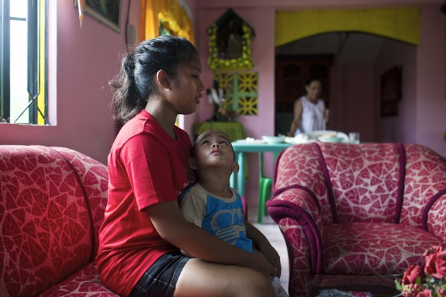 In this Nov. 21, 2013 photo, Shylyny Therese Negru, 15, holds her youngest brother, Rainier Aaron Dacuno, 3, as they sit in a relative's home in the town of Burauen, the Philippines. The children are among an unknown number in the eastern Philippines who lost their parents to the massive Nov. 8 storm. 