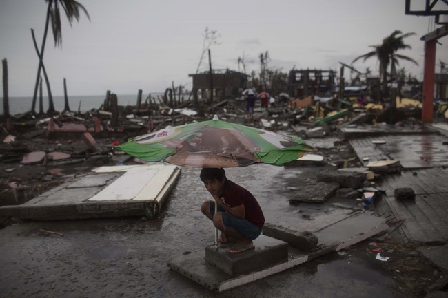 A Typhoon Haiyan survivor uses a market umbrella to protect himself from the rain in his destroyed neighborhood in Tacloban, Philippines, on Nov. 22.