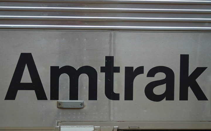 Amtrak logo on side of stainless steel Chicago bound train.