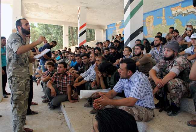 In this Tuesday, Aug. 13, 2013 citizen journalism image provided by Tawhid Brigade, which has been authenticated based on its contents and other AP reporting, Abdul-Qadir Saleh, left, the chief commander of the Tawhid Brigade, the main rebel outfit in Aleppo province, speaks to his fighters ahead of an attack on government troops, in Aleppo, Syria. 