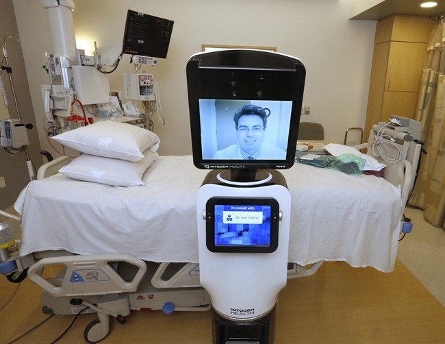 In this photo taken Wednesday, Nov. 6, 2013, Dr. Alan Shatzel, medical director of the Mercy Telehealth Network, is displayed on the monitor RP-VITA robot at Mercy San Juan Hospital in Carmichael, Calif. The robots enable physicians to have a different bedside presence as they "beam" themselves into hospitals to diagnose patients and offer medical advice during emergencies. (AP Photo/Rich Pedroncelli).