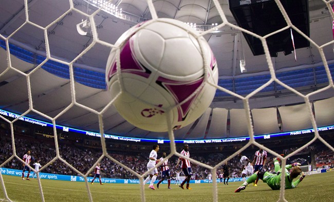 Vancouver Whitecaps' Gershon Koffie, 3rd right, of Ghana, scores a goal against a diving Chivas USA goalkeeper Dan Kennedy, lower right, during the first half of an MLS soccer game in Vancouver, B.C., on Wednesday October 3, 2012. THE CANADIAN PRESS/Darryl Dyck.