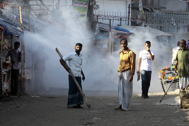 A Bangladeshi man armed with a bamboo reacts to the tear gas fired by the police as they gathered for a protest in front of a closed factory in Gazipur, on the outskirts of Dhaka, Bangladesh, Tuesday, Nov. 19, 2013. 