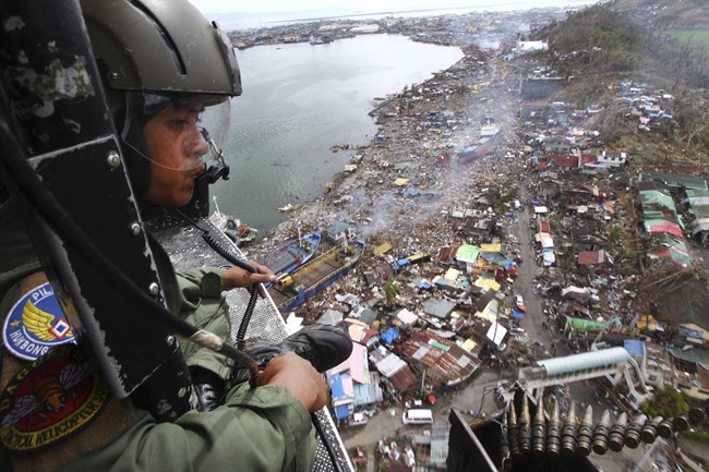 A Philippine Air Force crew looks out from his helicopter over Typhoon Haiyan-ravaged city of Tacloban in Leyte province, Philippines, Tuesday, Nov. 19, 2013.