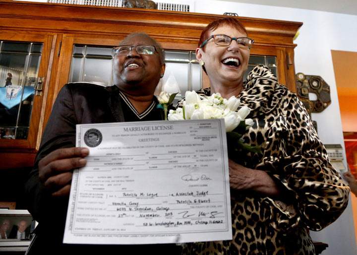 Holding their Illinois marriage license, Vernita Gray, left, and Patricia Ewert smile at friends after they were married by Cook County Judge Patricia Logue, the first gay marriage in Illinois, at the couple's home Wednesday, Nov. 27, 2013, in Chicago. 