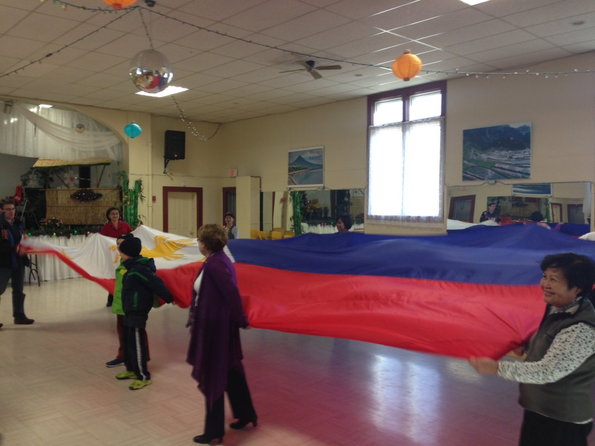 The Filipino Seniors Group of Winnipeg opens the flag as they raise funds for victims.