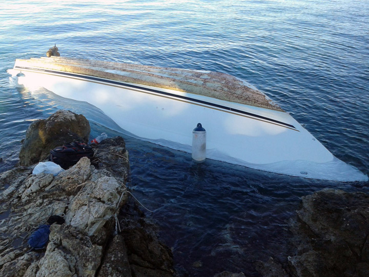This image made available by the Hellenic Coast Guard Friday, Nov. 15, 2013, shows a capsized boat on the coast of Lefkada, an island in the Ionian Sea, western Greece. Twelve migrants were found dead Friday and a further 15 were rescued after the boat capsized in western Greece, authorities said. 