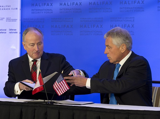 Canadian Defence Minister Rob Nicholson, left, and U.S. Secretary of Defence Chuck Hagel sign a Canada-U.S. Asia-Pacific defence agreement at the Halifax International Security Forum in Halifax on Friday, Nov. 22, 2013. THE CANADIAN PRESS/Andrew Vaughan.
