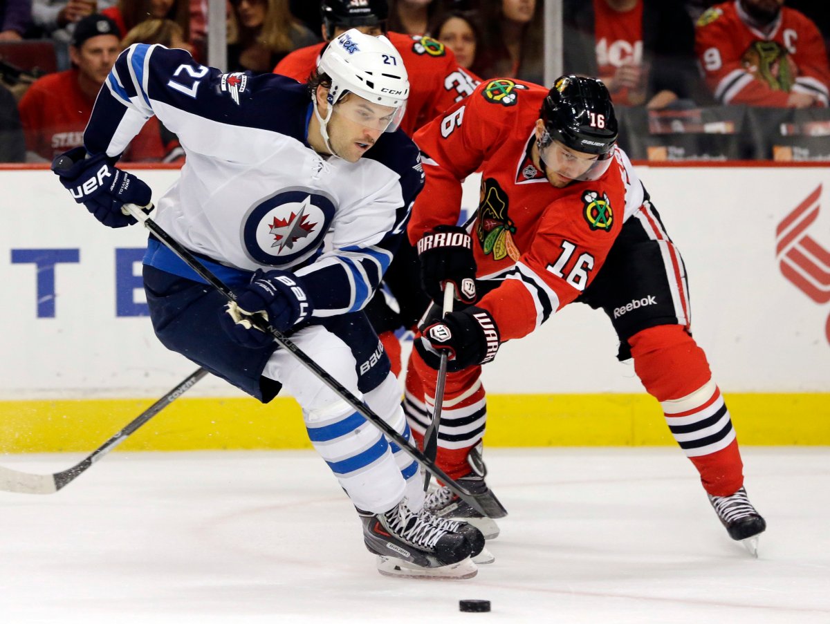 Winnipeg Jets' Eric Tangradi (27) controls the puck against the Chicago Blackhawks' Marcus Kruger (16) during the first period of an NHL hockey game in Chicago on Wednesday.