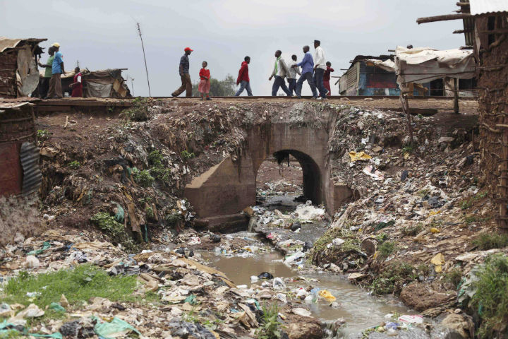 Slum dwellers cross a bridge over a stream of raw sewage, in the Kibera slum in Nairobi, Kenya, Wednesday May 27, 2009. 