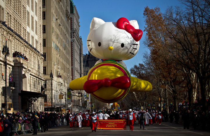 Spectators watch as the Hello Kitty balloon floats above the street during the Macy’s Thanksgiving Day Parade on November 28, 2013 in New York City.
