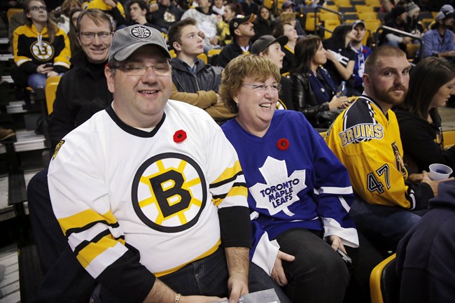 Tracy MacKenzie, left, and his wife Kim, from Nova Scotia, wait for the start of an NHL hockey game between the Boston Bruins and the Toronto Maple Leafs in Boston, Saturday, Nov. 9, 2013. (AP Photo/Michael Dwyer).