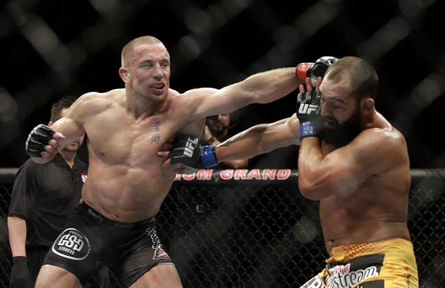 Johny Hendricks, right, exchanges punches with Georges St. Pierre, of Canada, during a UFC 167 mixed martial arts championship welterweight bout on Saturday, Nov. 16, 2013, in Las Vegas. St. Pierre won by split decision. (AP Photo/Isaac Brekken).