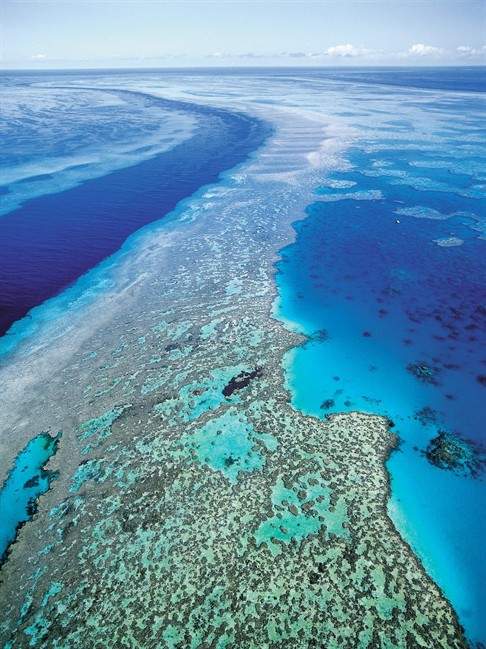 In this Sept. 2001 file photo provided by provided by Queensland Tourism, an aerial view shows the Great Barrier Reef off Australia's Queensland state. Starvation, poverty, flooding, heat waves, droughts, war and disease already lead to human tragedies. They're likely to worsen as the world warms from man-made climate change, a leaked draft of an international scientific report forecasts. Australia and New Zealand get the unique risk of losing their coral reef ecosystems, and small island nations have to be worried about being inundated by rising seas. (AP Photo/Queensland Tourism, File) .