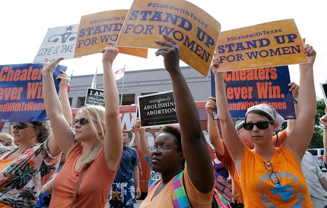 In this July 9, 2013, file photo, opponents and supporters of an abortion bill hold signs near a news conference outside the Texas Capitol, in Austin, Texas. 