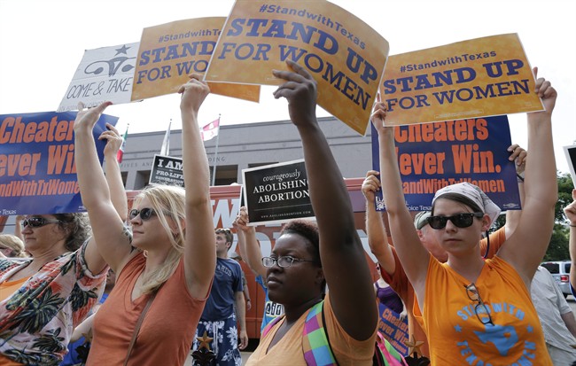 In this July 9, 2013, file photo, opponents and supporters of an abortion bill hold signs near a news conference outside the Texas Capitol, in Austin, Texas. 
