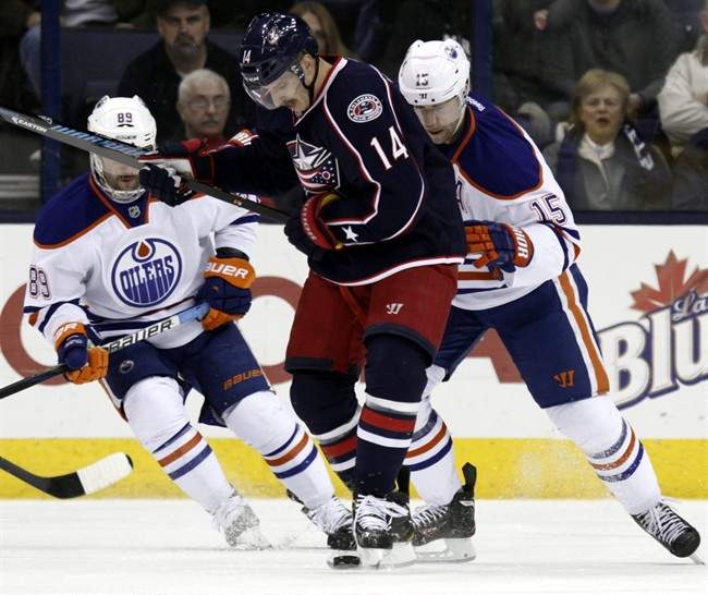 Columbus Blue Jackets' Blake Comeau (14) works for the puck between Edmonton Oilers' Sam Gagner (89) and Nick Schultz (15) in the first period of an NHL hockey game in Columbus, Ohio, Friday, Nov. 29, 2013.