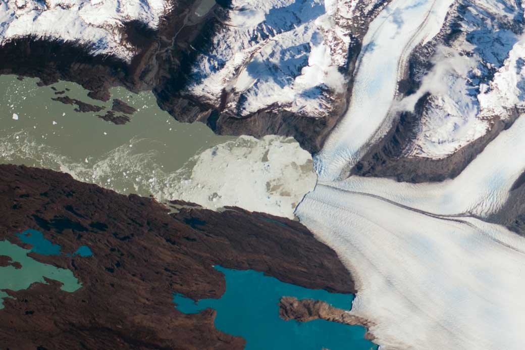 This photograph, taken by astronauts aboard the ISS, shows the Upsala Glacier. Dark lines of rocky debris (moraine) within the ice give a sense of the slow ice flow from right to left.