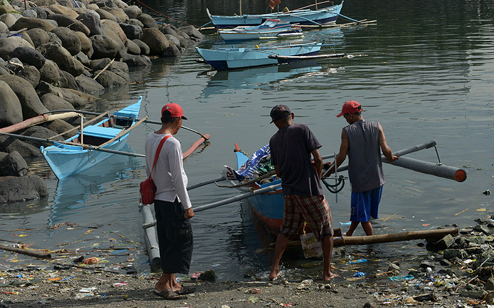 Fisherman repair their outrigger on the shore of Manila bay as Typhoon Haiyan approached on Thursday.
