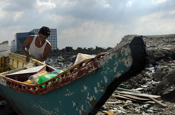 Fisherman repair there outrigger on the shore of Manila bay as Typhoon Haiyan approached on November 7, 2013. (Photo credit: Getty Images)
