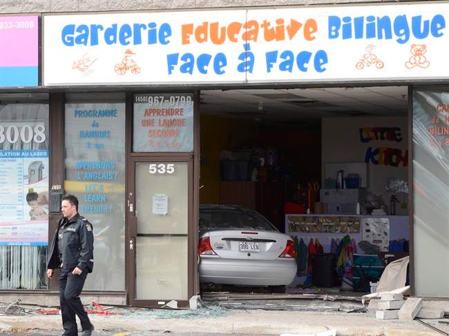 A police officer surveys the scene after a car crashed into a daycare centre in Laval, Que., Tuesday, Nov.12, 2013.