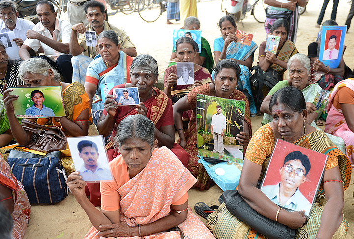 Sri Lankan members of the ‘Dead and Missing Person’s Parents’ organisation hold photographs as they take part in a protest in Jaffna, some 400 kilometres (250 miles) north of Colombo on November 15, 2013. (Photo credit: Getty Images)