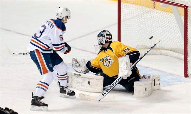 Edmonton Oilers forward Ryan Nugent-Hopkins, left, scores against Nashville Predators goalie Marek Mazanec (39), of Czech Republic, in the second period of an NHL hockey game Thursday, Nov. 28, 2013, in Nashville, Tenn. 