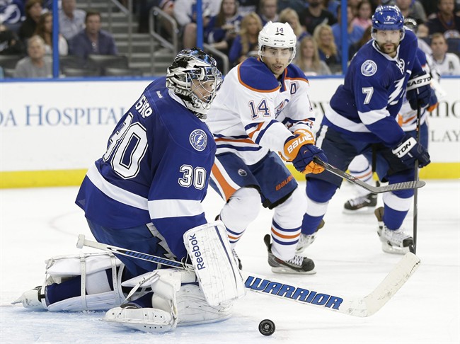 Tampa Bay Lightning goalie Ben Bishop (30) makes a save on a shot by Edmonton Oilers right wing Jordan Eberle (14) during the third period of an NHL hockey game on Thursday, Nov. 7, 2013, in Tampa, Fla. Tampa Bay's Radko Gudas (7) looks on. 