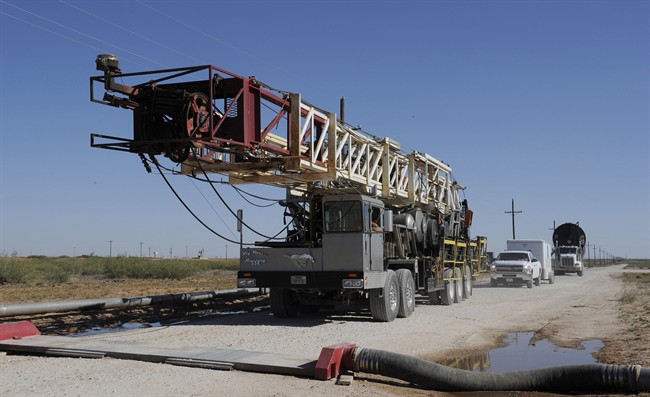 A drilling rig used for hydraulic fracturing is trucked across a water hose at a drill site Sept. 24, 2013, in Midland, Texas.