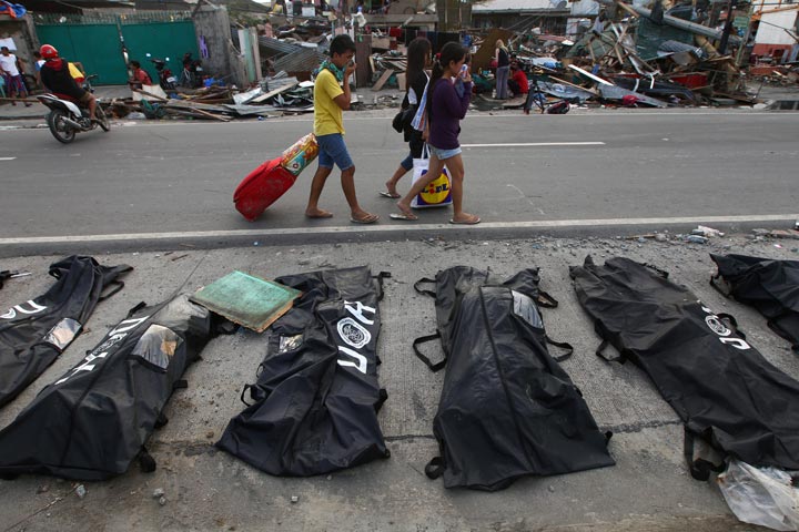 People cover their noses from the stench of dead bodies in an area affected by Typhoon Haiyan in Tacloban, Philippines, Wednesday, Nov. 13, 2013. Dita Alangkara / AP Photo.