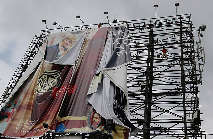 Filipino workers bring down a giant billboard along a busy highway as they prepare for the possible effects of powerful Typhoon Haiyan in suburban Makati, south of Manila, Philippines Thursday, Nov. 7, 2013. (Photo credit: AP Photo)