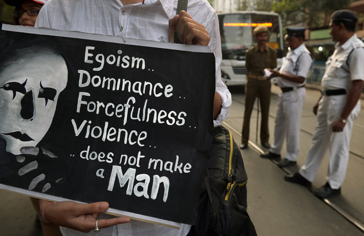 An Indian social activist holds a placard as policemen (background R) look on during a rally on the International Day for the Elimination of Violence against Women in Kolkata on November 25, 2013. 