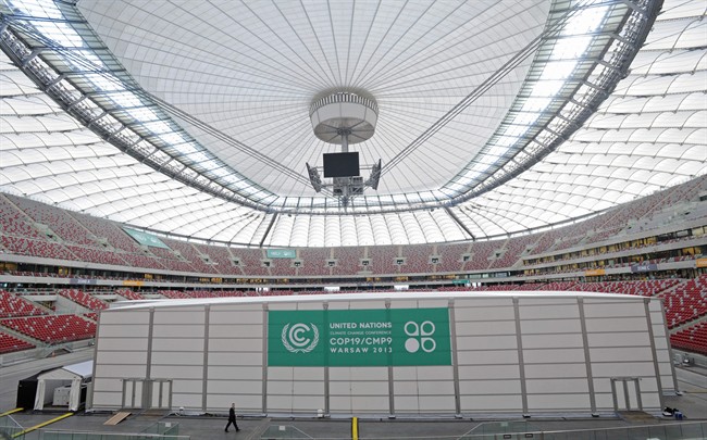A man walks past special halls set on the pitch of the National Stadium, the venue of the U.N. Climate Change Conference, in Warsaw, Poland, Sunday, Nov. 10, 2013. 