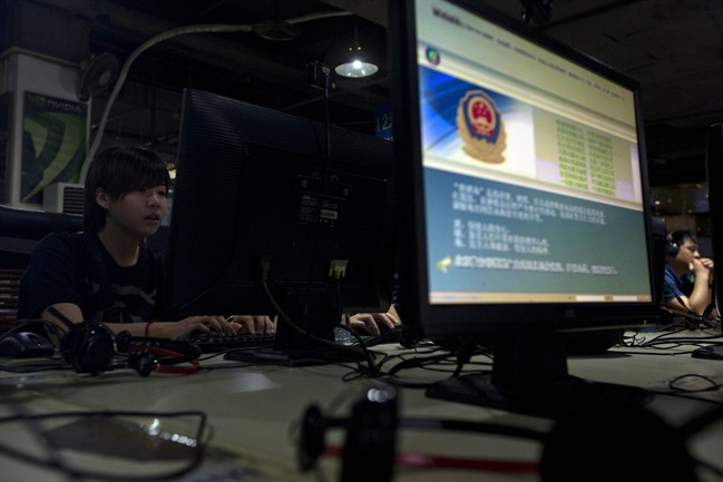 In this Monday, Aug. 19, 2013 file photo, computer users sit near a display with a message from the Chinese police on the proper use of the internet at an internet cafe in Beijing, China.