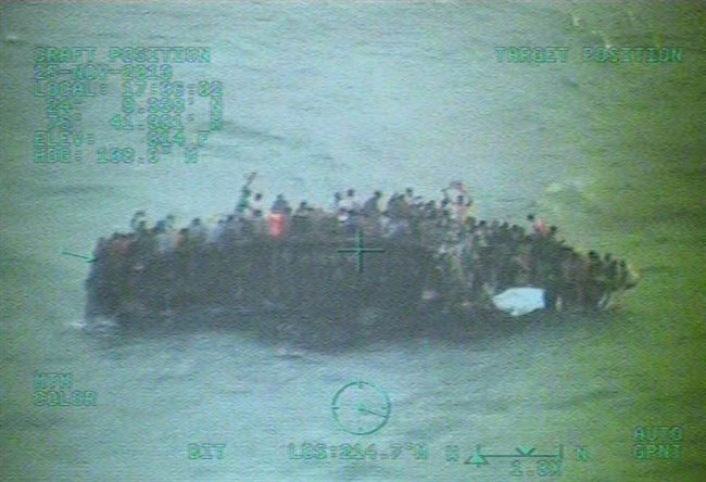 This image taken from video made available by the U.S. Coast Guard shows a group of Haitian migrants sitting on the hull of a capsized sailboat near Staniel Cay, Bahamas, Tuesday, Nov. 26, 2013. 