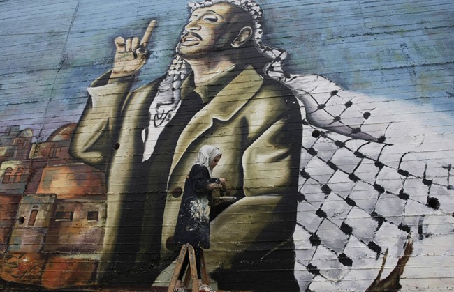 Palestinian Hanadi Kharma, paints a mural depicting the late Palestinian leader Yasser Arafat in the West Bank city of Nablus, Thursday, Nov. 7, 2013. 