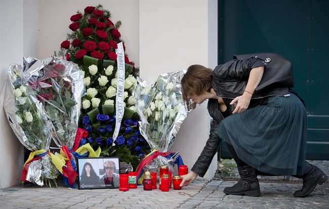 A Romanian journalist places a candle next to photographs of French RFI radio journalists Ghislaine Dupont and Claude Verlon outside the French embassy in Bucharest, Romania, Monday, Nov. 4, 2013. 