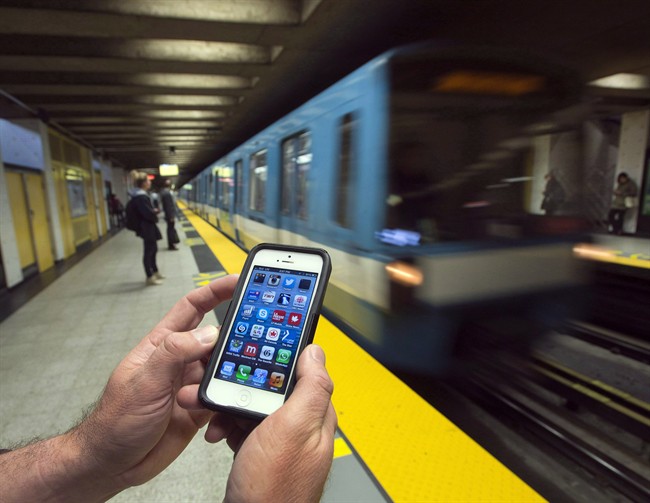 A commuter looks at his smart phone on the Metro Wednesday, September 25, 2013 in Montreal.