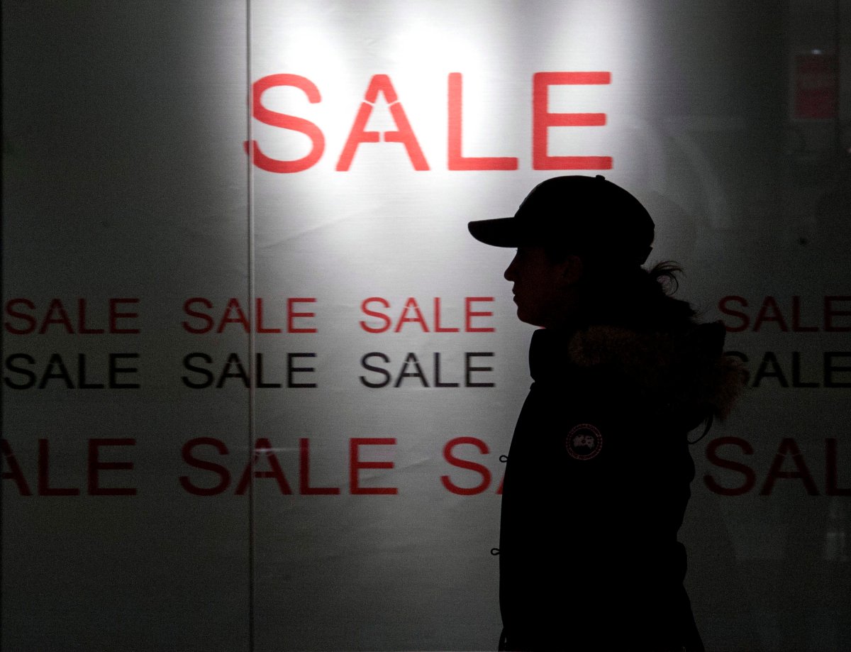 A shopper walks by a store display advertising a Boxing Day sale in Ottawa on Thursday, Dec. 26, 2013. 