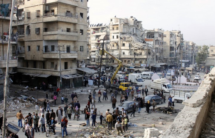 Syrians look at the aftermath of airstrikes by government forces on the northern Syrian city of Aleppo on November 24, 2013.