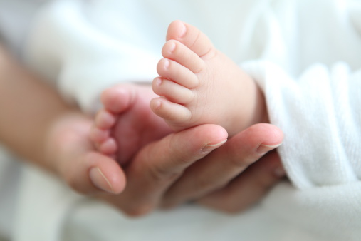 A newborn baby's feet in their parent's hand.