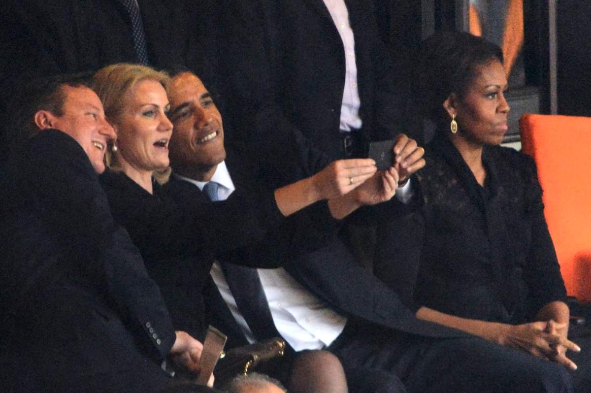 President Barack Obama (R) and British Prime Minister David Cameron pose for a picture with Denmark's Prime Minister Helle Thorning Schmidt (C) next to US First Lady Michelle Obama (R) during the memorial service of South African former president Nelson Mandela at the FNB Stadium (Soccer City) in Johannesburg on December 10, 2013.