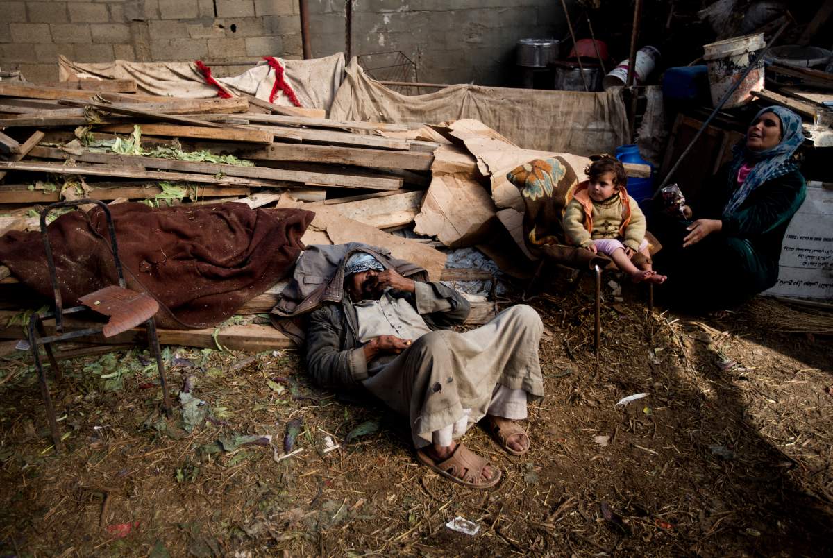 A Palestinian family sits outside its house in a flooded area of Gaza city on December 15, 2013. (Mahmud Hams, AFP/Getty Images)