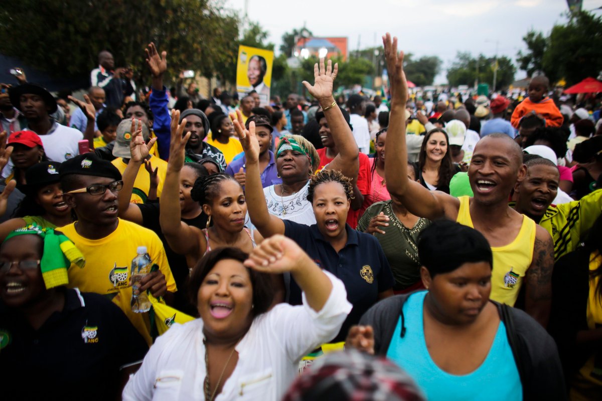 Members of the African National Congress (ANC) and mourners sing to celebrate the life of Nelson Mandela outside his old house in Soweto, Johannesburg, South Africa, Sunday, Dec. 8, 2013. (AP Photo/Markus Schreiber).